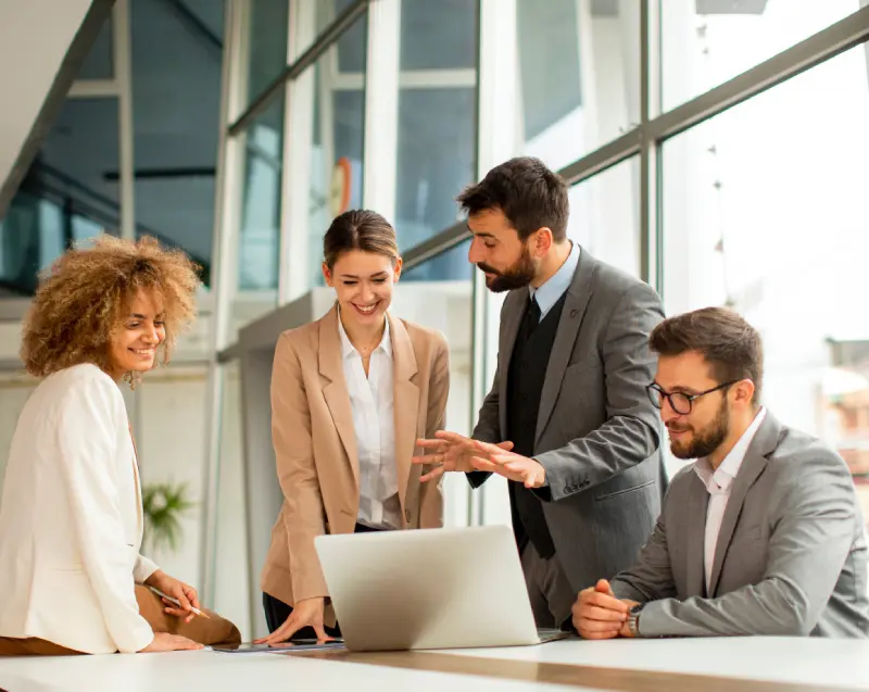Business professionals meeting around a laptop, representing collaboration across the diverse industries served.